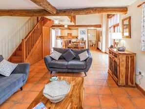 A spacious living area with a sofa, a coffee table, and a staircase leading to an upper floor.