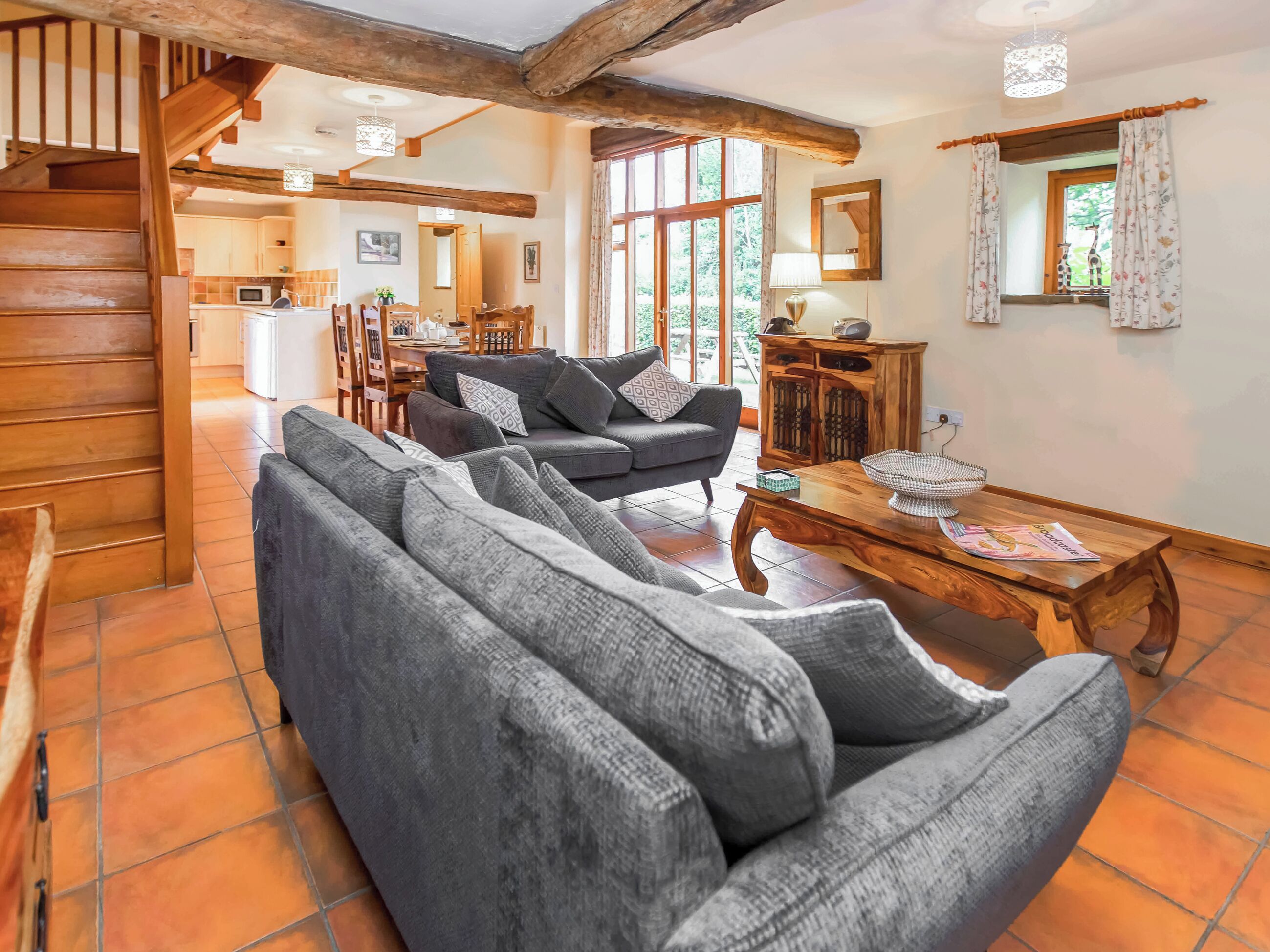 A cozy living room with a sofa, a wooden coffee table, and a staircase leading to an upper level.
