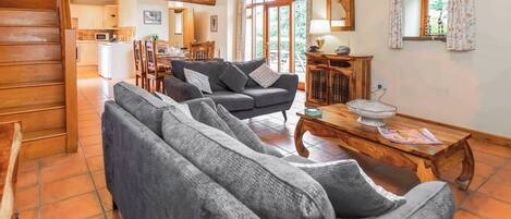 A cozy living room with a sofa, a wooden coffee table, and a staircase leading to an upper level.