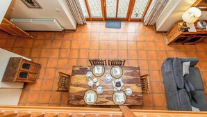 A dining area with a wooden table set for four, a sofa, and a view of a garden through large windows. - 2 bedroom accommodation in Catfield (Catfield)