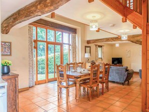 Un vaste espace dédié à la salle à manger, avec des meubles en bois, un téléviseur et une grande fenêtre donnant sur un paysage verdoyant.