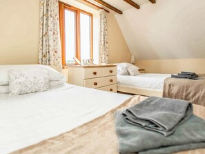 Une chambre avec deux lits, une commode et une fenêtre avec des rideaux.