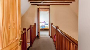A narrow hallway with wooden railings and a carpeted floor, leading to a room with a bed and a table. - 2 bedroom accommodation in Catfield (Catfield)