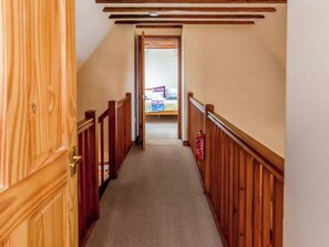 A narrow hallway with wooden railings and a carpeted floor, leading to a room with a bed and a table. - 2 bedroom accommodation in Catfield (Catfield)