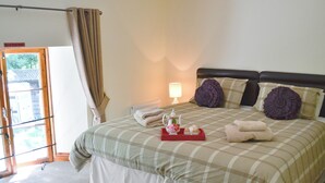 A neatly made bed with a checkered bedspread, two decorative pillows, and a tray with towels and a teapot. - The Coach House - EXG (Upton, near Dulverton)