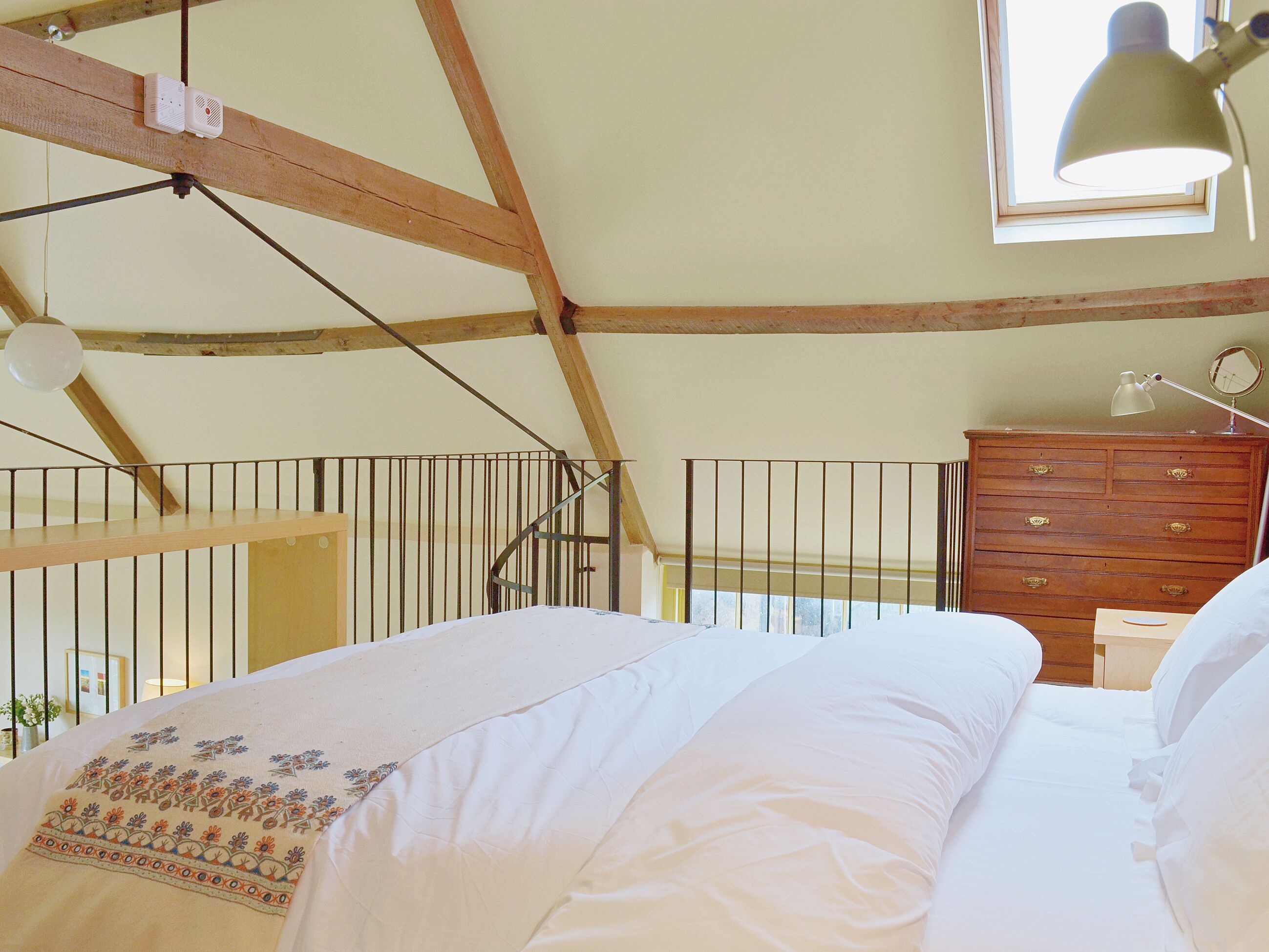 Un dormitorio con cama, cómoda, ventana y barandilla de balcón.