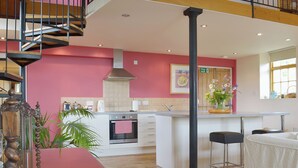 A kitchen with a central island, a staircase, and a dining area with a table and chairs. - 1 bedroom accommodation in Burcott, Wells (Burcott, Wells)