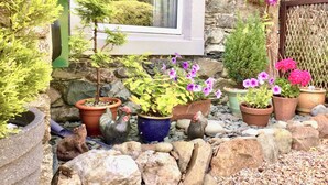 A garden with potted plants, a small tree, and a window overlooking greenery. - 2 bedroom accommodation in Bassenthwaite, near Keswick (Bassenthwaite, near Keswick)