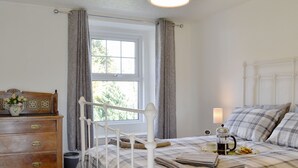 A bedroom with a bed, bedside table, lamp, and a view of the outdoors through a window. - 2 bedroom accommodation in Bassenthwaite, near Keswick (Bassenthwaite, near Keswick)