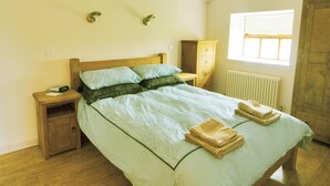 Un dormitorio con cama, mesita de noche, cómoda y ventana.