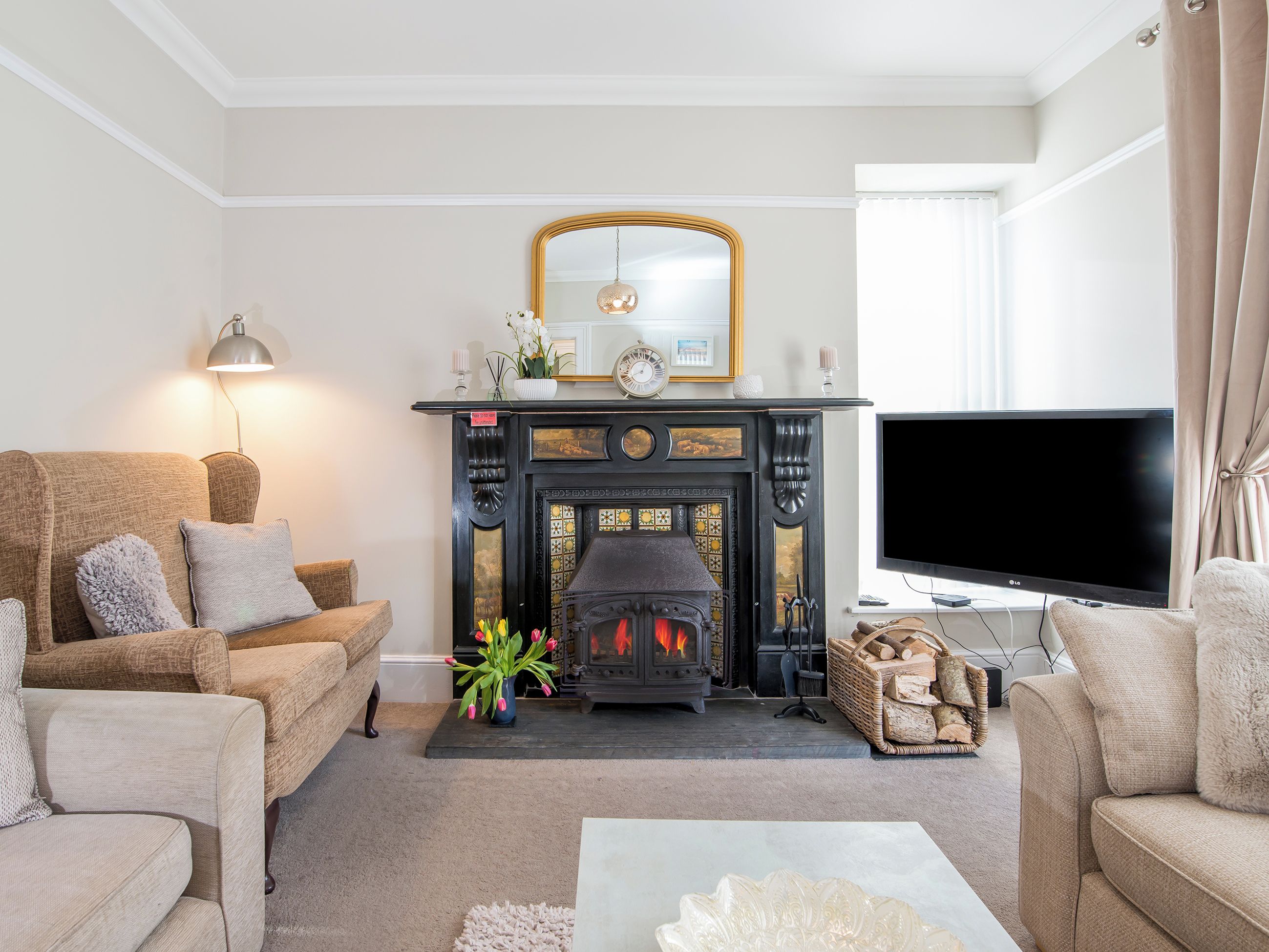 A living room with a fireplace, sofas, a television, and a mirror.