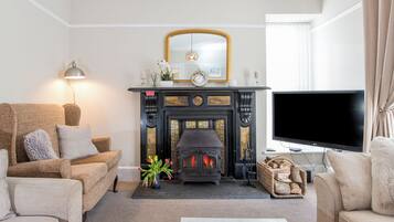 A living room with a fireplace, sofas, a television, and a mirror.