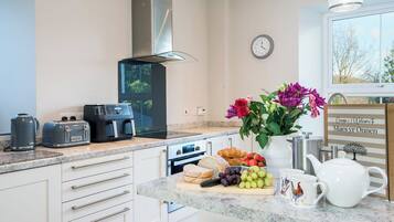 A modern kitchen with a built-in oven, a coffee maker, a toaster, and a clock on the wall.