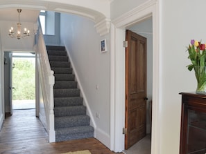 A staircase with carpeted steps leading to a door, a chandelier, and a vase with flowers. - 4 bedroom accommodation in Abercych, near Cardigan (Abercych, near Cardigan)