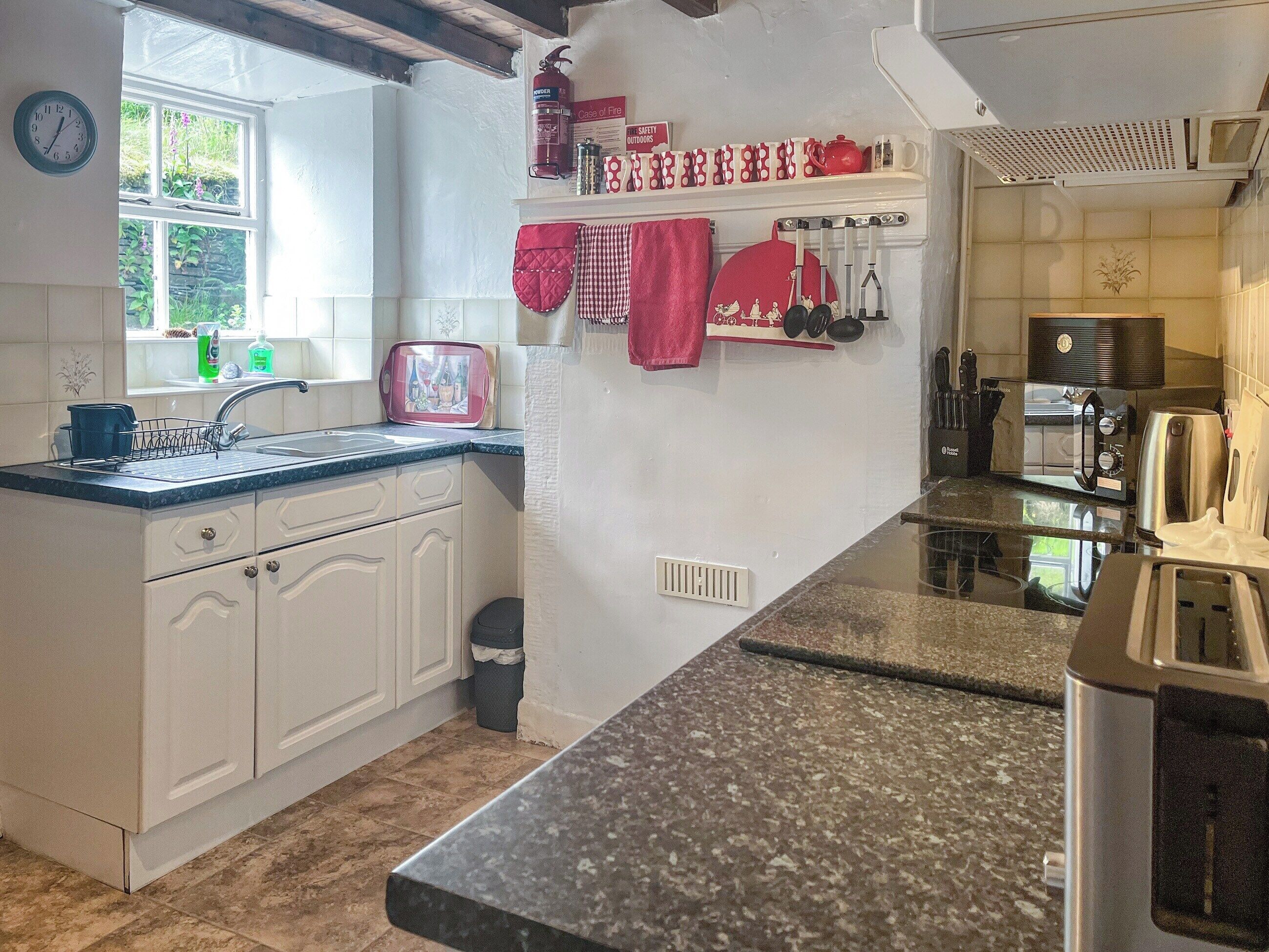 A kitchen with white cabinets, a granite countertop, a microwave, a toaster, and a sink.