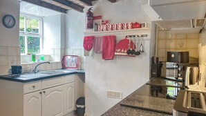 Una cucina con mobili bianchi, un piano di lavoro in granito, un forno a microonde, un tostapane e un lavello.