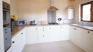 Een moderne keuken met witte kasten, een roestvrijstalen afzuigkap, een ingebouwde magnetron en een gasfornuis.