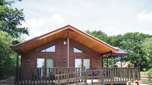 Een houten blokhut met een overdekte veranda en een klein terras.