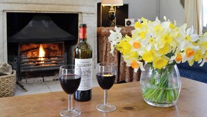 Une table avec deux verres à vin, une bouteille de vin Château Mouton Rothschild et un vase de jonquilles.