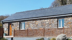 A stone building with a wooden door, windows, and a fenced porch. - 3 bedroom accommodation in Dihewyd, near Aberaeron (Dihewyd, near Aberaeron)