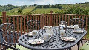 A table set outdoors with chairs, a view of green fields, and a cloudy sky. - 3 bedroom accommodation in Dihewyd, near Aberaeron (Dihewyd, near Aberaeron)