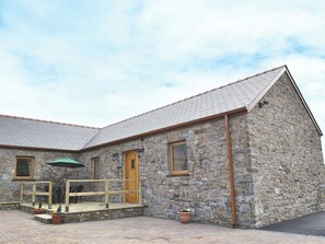A stone building with a sloped roof, wooden door, and windows.