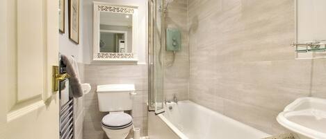 Een badkamer met toilet, douche en bad.