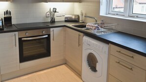 A modern kitchen with a built-in oven, a dishwasher, and a window providing natural light. - 1 bedroom accommodation in Whitby (Whitby)