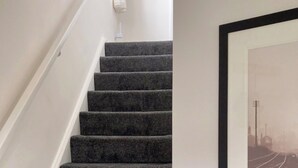 Un escalier dont les marches sont recouvertes de moquette, menant à un palier.