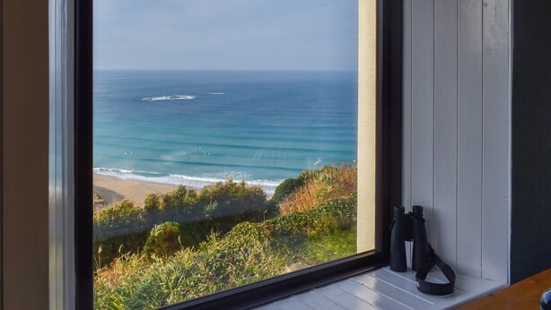 Ein großes Fenster mit Blick auf das Meer und den Strand.