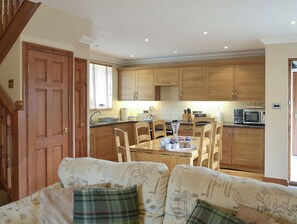 A cozy kitchen with wooden cabinets, a dining table with chairs, and a staircase leading to an upper floor.