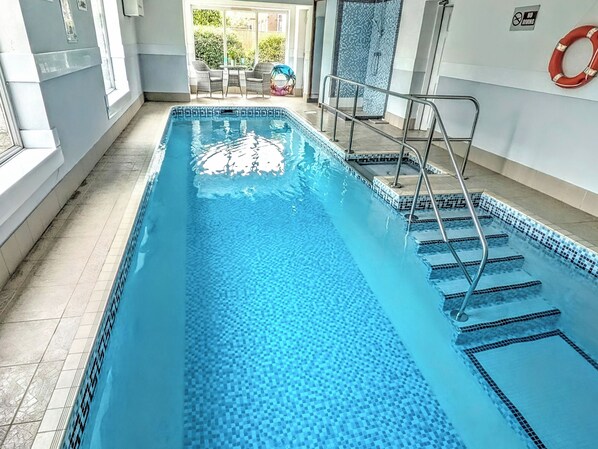An indoor swimming pool with clear water, a lifebuoy on the wall, and a view of the outside. - 5 bedroom accommodation in Potter Brompton, Scarborough (Potter Brompton, Scarborough)