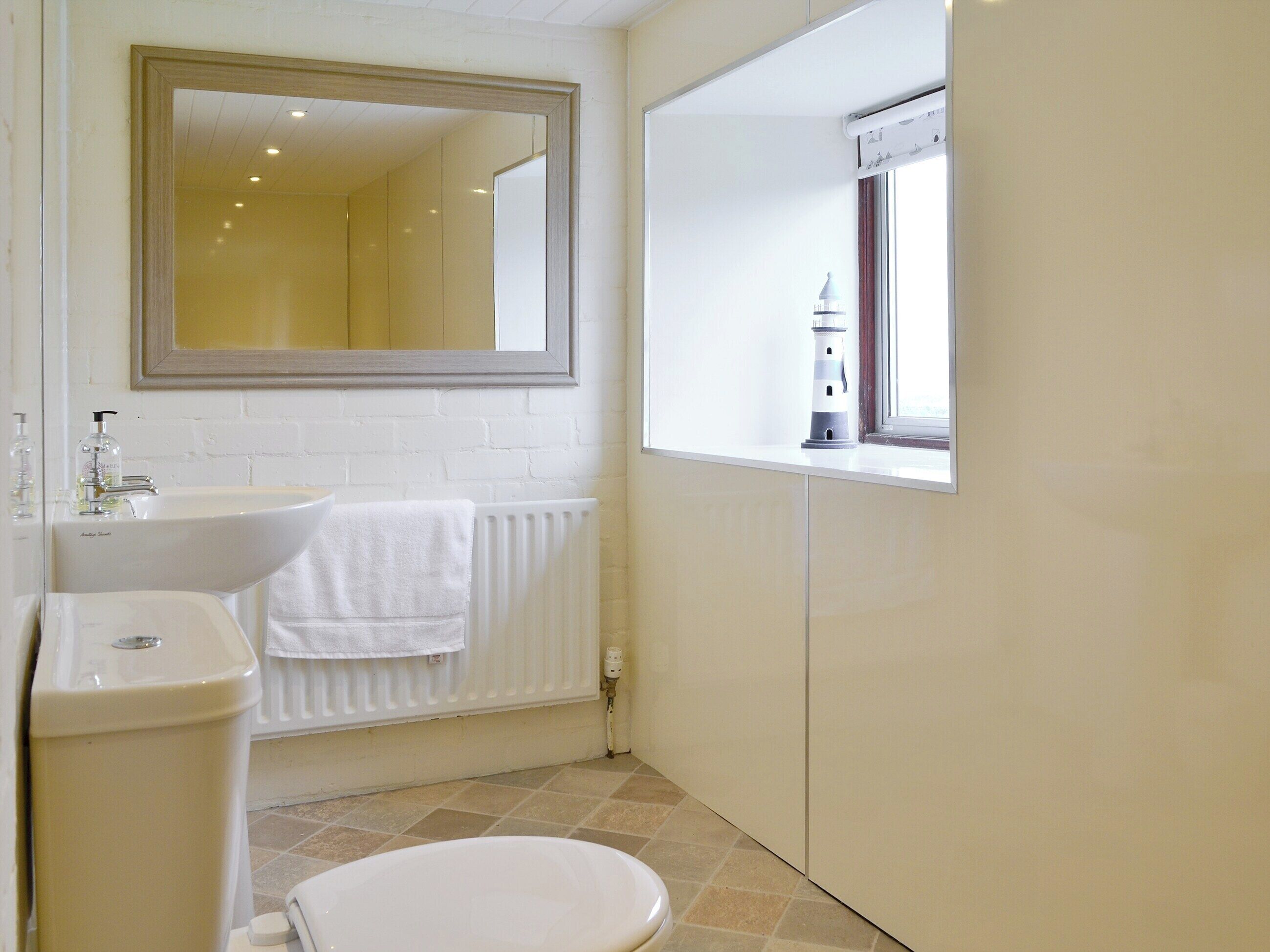 Un baño con un lavamanos blanco, un inodoro y un espejo sobre el lavamanos.