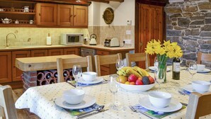 A dining area with a table set for four, including a fruit bowl, wine glasses, and a bottle of wine. - 4 bedroom accommodation in Holy Island, near Berwick-upon-Tweed (Holy Island, near Berwick-upon-Tweed)