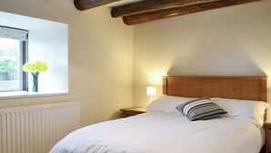A neatly made bed with white linens, a wooden headboard, a bedside lamp, and a window with a view of greenery. - 4 bedroom accommodation in Holy Island, near Berwick-upon-Tweed (Holy Island, near Berwick-upon-Tweed)