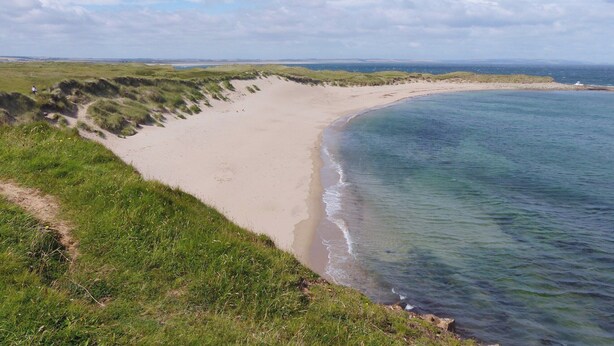 A coastal landscape with a sandy beach and grassy dunes. - 4 bedroom accommodation in Holy Island, near Berwick-upon-Tweed (Holy Island, near Berwick-upon-Tweed)