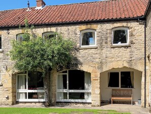 A stone building with a tiled roof, multiple windows, and a bench outside. - 3 bedroom accommodation in Pickering (Pickering)