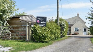 Un cadre rural avec un panneau indiquant l’emplacement d’un centre de bien-être et donnant les directions vers « The Spa at Hornby » et « Globe Farm House ».