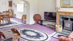 Un salon doté d’une cheminée, d’un téléviseur et d’un coin repas avec des chaises et une table.