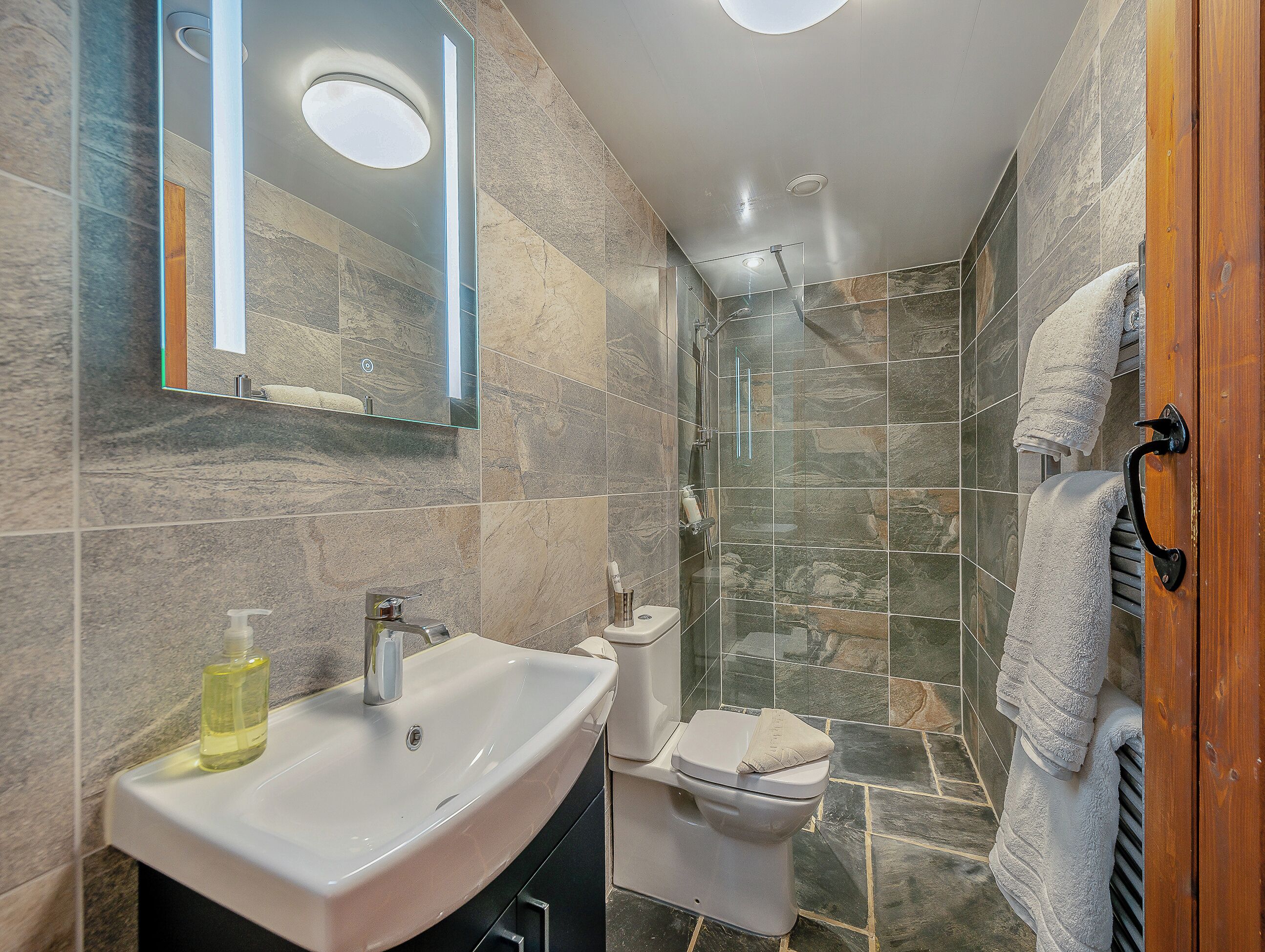 A bathroom with a sink, mirror, toilet, and shower.
