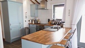 A kitchen with a wooden countertop, a sink, a stove, and a microwave.