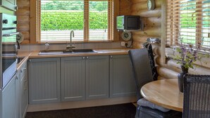 A kitchen with a wooden interior, a sink, cabinets, a dining area with a table and chairs, and a television mounted on the wall. - 1 bedroom accommodation in South Carlton, near Lincoln (South Carlton, near Lincoln)