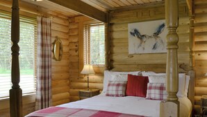 A log cabin bedroom with a four-poster bed, plaid bedding, a mirror, and a painting of an owl. - 1 bedroom accommodation in South Carlton, near Lincoln (South Carlton, near Lincoln)