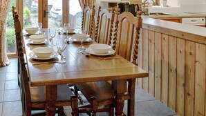 A wooden dining table set with plates, bowls, and wine glasses, surrounded by chairs with carved wooden backs. - 3 bedroom accommodation in Thornton Rust, near Leyburn (Thornton Rust, near Leyburn)