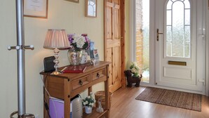 A wooden console table with a lamp, a vase with flowers, framed certificates, and a small dog figurine. - 2 bedroom accommodation in Graigfechan, near Ruthin (Graigfechan, near Ruthin)