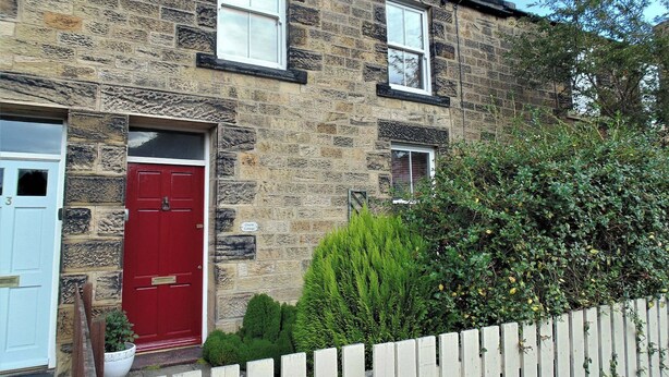 A stone building with a red door, a white door, and a small window. - 2 bedroom accommodation in Alnwick (Alnwick)