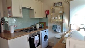 A compact kitchen with a stove, oven, washing machine, and a small sink. - 2 bedroom accommodation in Alnwick (Alnwick)