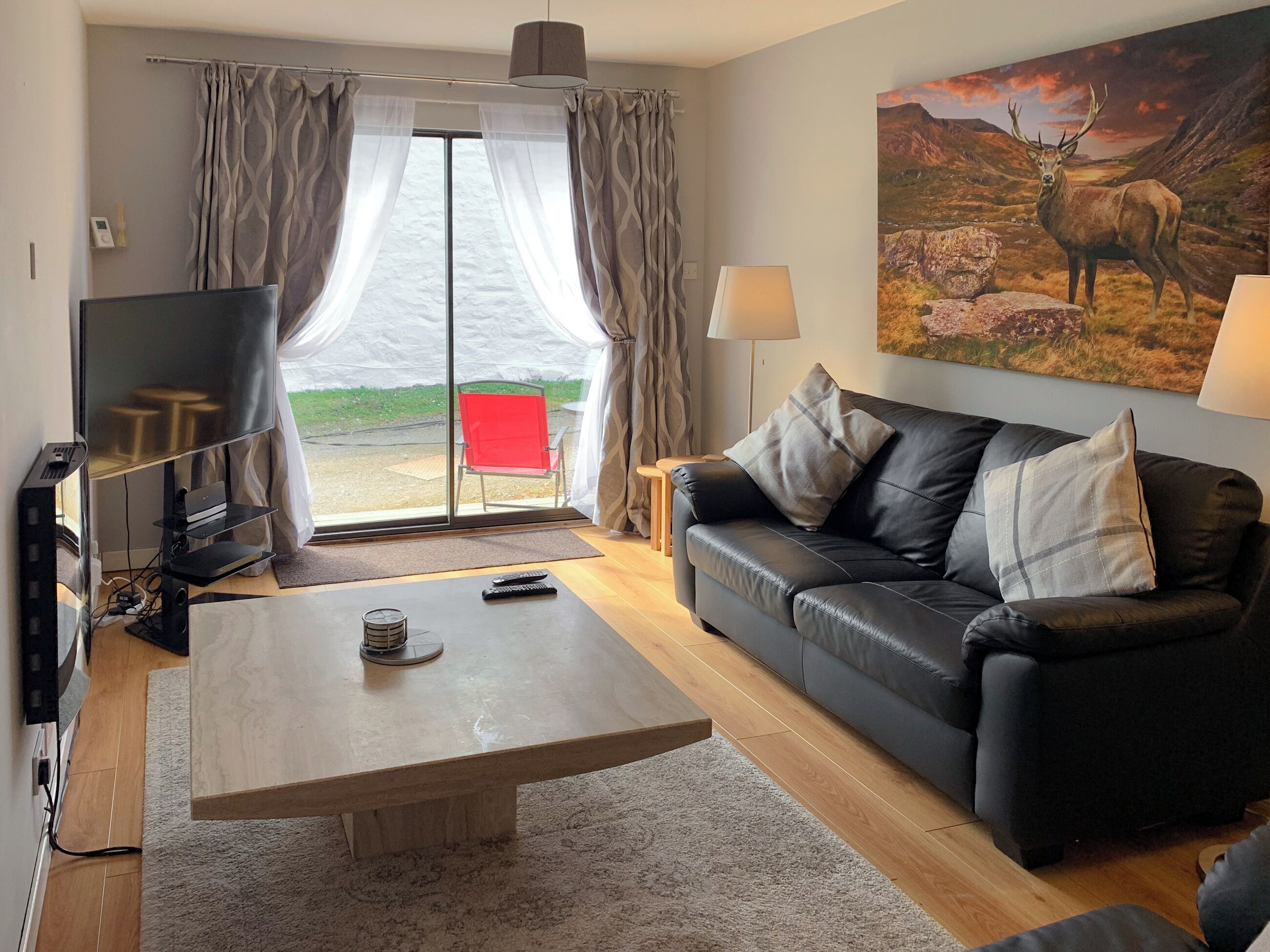 A living room with a sofa, a coffee table, a TV, and a painting of a deer.