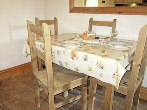 Une table à manger en bois, recouverte d’une nappe à motifs floraux, entourée de chaises en bois.