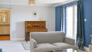 A living room with a beige sofa, a glass coffee table, a wooden cabinet, and a blue wall. - 3 bedroom accommodation in Edinburgh (Edinburgh)
